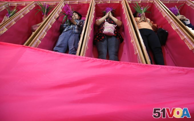 Worshippers pray as they take turns lying in coffins at the Takien temple in suburban Bangkok, Thailand Monday, Dec. 31, 2018.