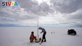 State biologists collects water samples in the Bonneville Salt Flats Tuesday, Sept. 13, 2022, near Wendover, Utah. The glistening white salt of the world famous area is shrinking near the Utah-Nevada line. (AP Photo/Rick Bowmer)