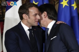 FILE - In this Thursday, Feb. 27, 2020 file photo, French President Emmanuel Macron, left, puts his arm around the shoulder of Italian Premier Giuseppe Conte and gives him a kiss on both cheeks. (AP Photo/Andrew Medichini, File)