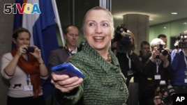 In this Dec. 8, 2011, file-pool photo, then-Secretary of State Hillary Clinton hands off her mobile phone after arriving for a meeting in The Hague, Netherlands. (AP Photo/J. Scott Applewhite, FILE)