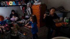Deneffy S<I>&#</I>225;nchez, left, looks at his smartphone on a bunk bed he shares with his mother, Lilian Lopez, right, and sister, Jennifer, in a shared studio apartment in Los Angeles, Saturday, Sept. 9, 2023. (AP Photo/Jae C. Hong)