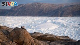 FILE - In this Aug. 16, 2019 photo, NYU student researchers sit on top of a rock overlooking the Helheim glacier in Greenland.(AP Photo/Felipe Dana)