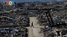  In this March 27, 2011 file photo, a man walks through an earthquake destroyed neighborhood below Weather Hill in Natori, Japan. (AP Photo/Wally Santana, File)