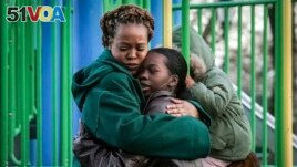 Derry Oliver, 17, right, hugs her mother, also Derry Oliver, during a visit to a playground near home, Friday, Feb. 9, 2024, in New York. (AP Photo/Bebeto Matthews)