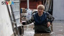A woman walks near her house in a flooded area in Orenburg, Russia, Wednesday, April 10, 2024. (AP Photo)