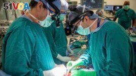 In this photo provided by Duke Health, surgeons Dr. Jacob Schroder, left, and Dr. Zachary Fitch perform a heart transplant at Duke University Hospital in Durham, N.C., in October 2022. (Shawn Rocco/Duke Health via AP)