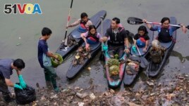 Environmental activist members of the Situ Gede Cleanliness Warrior pick up trash while paddling kayaks at Setu Gede lake in Bogor, West Java, Indonesia, Tuesday, Oct. 10, 2023. (AP Photo/Achmad Ibrahim)