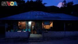 Bara Kilimandang stands at the door of his house whose electricity comes from solar energy in Walatungga on Sumba Island, Indonesia, Tuesday, March 21, 2023. (AP Photo/Dita Alangkara)