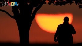 FILE - A woman watches the sun sets on a hot day, Aug. 20, 2023, in Kansas City, Mo. A new study on May 14, 2024, finds that the summer of 2023 was the hottest in the Northern Hemisphere in more than 2,000 years. (AP Photo/Charlie Riedel, File)
