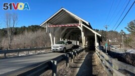 A vehicle passes through the Miller's Run covered bridge in Lyndon, Vt., on Tuesday, March 12, 2024. The historic bridge is under threat from truck drivers relying on GPS meant for cars continually hitting the bridge. (AP Photo/Lisa Rathke)