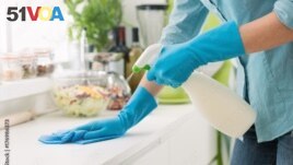 FILE - A person cleans a counter with a spray cleaner. (Adobe)