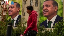 A person walks past billboards of Turkish President and People's Alliance's presidential candidate Recep Tayyip Erdogan a day after the presidential election day, in Istanbul, Turkey, Monday, May 15, 2023. (AP Photo/Emrah Gurel)