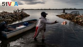 Tereha Davis tosses a conch shell off to the side as she prepares to launch her boat to go conch fishing off the coast of McLean's Town, Grand Bahama Island, Bahamas, Monday, Dec. 5, 2022. (AP Photo/David Goldman)