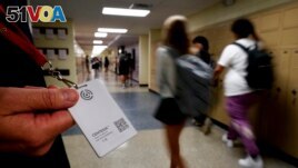FILE - Brent Kiger, Olathe Public Schools' director of safety service, displays a panic-alert button while students at Olathe South High School rush between classes, Aug. 19, 2022, in Olathe, Kansas. (AP Photo/Charlie Riedel, File)