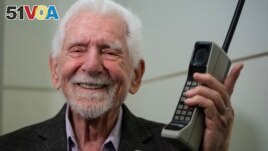 FILE - Martin Cooper, the inventor of first commercial mobile phone, poses with a Motorola DynaTAC 8000x during an interview with The Associated Press at the Mobile World Congress 2023 in Barcelona, Spain, Feb. 27, 2023. (AP Photo/Joan Mateu Parra)