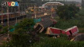 A passenger train passes by the site where two passenger trains derailed Friday in Balasore district, in the eastern Indian state of Orissa, Monday, June 5, 2023. (AP Photo/Rafiq Maqbool)
