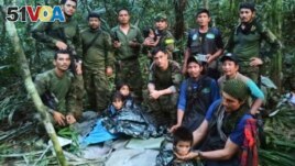 In this photo released by Colombia's Armed Forces Press Office, soldiers and Indigenous men pose for a photo with the four Indigenous brothers who were missing after a deadly plane crash, in the Solano jungle, Caqueta state, Colombia, June 9, 2023. 
