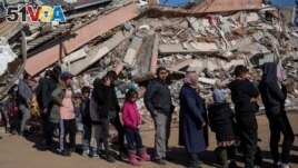 People line up for food served amid the rubble following the deadly earthquake in Kahramanmaras, Turkey, February 16, 2023. (REUTERS/Eloisa Lopez)