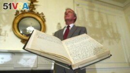 FILE - Archivist of the U.S John Carlin stands behind a 1947 Harry Truman presidential diary, July 10, 2003, at the National Archives in Washington. Presidents from George Washington to Joe Biden have kept presidential diaries. (AP Photo/Rick Bowmer, File)