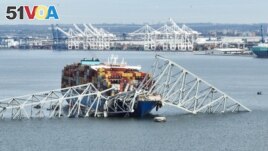 In this aerial image, the steel frame of the Francis Scott Key Bridge sits on top of a container ship after the bridge collapsed, in Baltimore, Maryland, on March 26, 2024. (Photo by Jim WATSON / AFP)