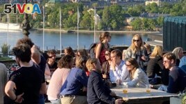 People enjoy drinks and snacks in the evening sun on a terrace overlooking Stockholm, on Tuesday, May 30, 2023. Smoking is prohibited in both indoor and outdoor areas of bars and restaurants in Sweden. (AP Photo/Karl Ritter)
