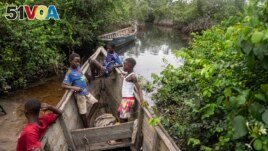 Children sit inside a fishing boat outside a mangrove in Kimpozia village, one of the areas auctioned for oil drilling, in Moanda, Democratic Republic of the Congo, Monday, Dec. 25, 2023. (AP Photo/Mosa'ab Elshamy)