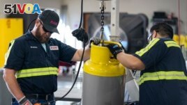 Operators move a used refrigerant cylinder at the A-Gas Rapid Recovery DFW facility on Monday, Oct. 9, 2023, in Arlington, Texas. (AP Photo/Sam Hodde)