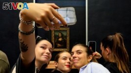 FILE - Visitors take pictures of themselves with the famous Leonardo Da Vinci's Mona Lisa at the Louvre in Paris, France on Sept. 11, 2022. (Photo by Hai Do)