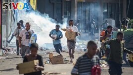 People run with merchandise as crowds leave shops with looted goods amid a state of unrest in Port Moresby on Jan. 10, 2024. (Andrew Kutan—AFP/Getty Images)
