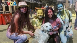 FILE - People pose with a dog covered in colour powder during the first color run called 