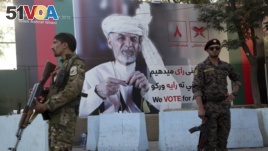 Afghan security forces stand guard in front of an election poster for presidential candidate Ashraf Ghani in Kabul, Afghanistan, Sept. 23, 2019. 