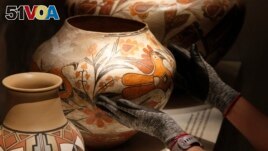 Finishing touches are made on a community-curated exhibition of Native American pottery from the Pueblo Indian region of the U.S. Southwest on July 28, 2022, at the Museum of Indian Arts and Culture in Santa Fe, N.M. (AP Photo/Morgan Lee)
