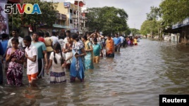 Residents wade through a flooded street as they evacuate their homes in Chennai, in the southern state of Tamil Nadu, India, Dec. 3, 2015.  