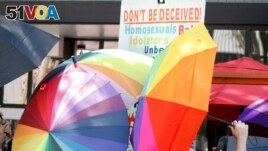 FILE - A sign-carrying anti-gay protester is surrounded by a sea of Pride umbrellas during the Pride parade in Winston-Salem, N.C., June 18, 2022. (AP Photo/Skip Foreman, File)