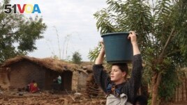 FILE - Cameron Beach, carries a carries a bucket of water on her head collected from a communal borehole in Dedza, near Lilongwe, Malawi, on July 23, 2021. The Peace Corps says it'll start sending volunteers overseas again in mid-March.