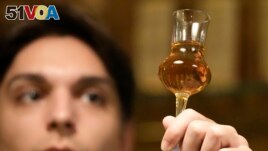 A barman looks at a glass with plum brandy in a bar in Belgrade, Serbia, Friday, Nov. 11, 2022. (AP Photo/Darko Vojinovic)