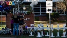 A family pays their respects next to crosses bearing the names of Tuesday's shooting victims at Robb Elementary School in Uvalde, Texas, May 26, 2022. (AP Photo/Jae C. Hong)
