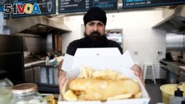 Owner of Hooked Fish and Chips shop, Bally Singh, holds a portion of fish and chips at his take-away in West Drayton, Britain, May 25, 2022. Picture taken May 25, 2022. (REUTERS/Peter Nicholls)