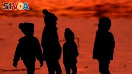 FILE - Children are silhouetted against a pond at a park in Lenexa, Kan., on Saturday, Dec. 26, 2020. Health officials remain perplexed by mysterious cases of severe liver damage in hundreds of young children around the world. (AP Photo/Charlie Riedel, File)