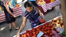 A woman buys tomatoes at a street market in Rio de Janeiro, Brazil, Wednesday, May 11, 2022. (AP Photo/Silvia Izquierdo)