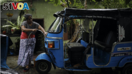 Lasanda Deepthi, 43, an auto-rickshaw driver for local ride hailing app PickMe, cleans her auto-rickshaw in Gonapola town, on the outskirts of Colombo, Sri Lanka, May 23, 2022. (REUTERS/Adnan Abidi)