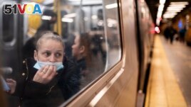 FILE - A passenger looks out onto the platform while riding a northbound train in the 36th Street subway station during the morning commute, in New York, April 13, 2022. 