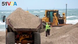 A dump truck brings another load of sand to an eroded beach in North Wildwood, New Jersey. A bulldozer spreads out sand, May 24, 2022. (File Photo)