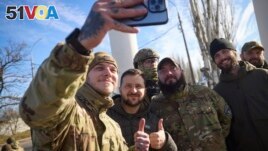 In this photo provided by the Ukrainian Presidential Press Office and posted on Facebook, Ukrainian soldiers take a selfie with President Volodymyr Zelenskyy, centre, during his visit to Kherson, Ukraine, Monday, Nov. 14, 2022. ((Ukrainian Presidential Press Office via AP)