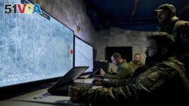 Ukrainian soldiers watch drone feeds from an underground command center in Bakhmut, Donetsk region, Ukraine, Sunday, Dec. 25, 2022. (AP Photo/Libkos)