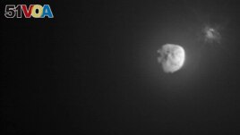 In this image made available by NASA, debris ejects from the asteroid Dimorphos, right, a few minutes after the intentional collision of NASA's Double Asteroid Redirection Test (DART) mission on Sept. 26, 2022, captured by the nearby Italian Space Agency'