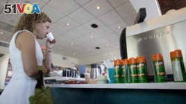 U.S. Congresswoman Debbie Wasserman Schultz, sips Cuban coffee next to a counter with cans of insect repellent. She held a news conference at David's Cafe Cafecito, Monday, Aug. 22, 2016, in Miami Beach, Florida and called for more federal help to fight Zika. (AP Photo/Wilfredo Lee)
