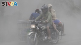 A family rides their motorcycle through clouds of ash as they evacuate to safer grounds as Taal volcano in Tagaytay, Cavite province, southern Philippines on Monday, Jan. 13, 2020. (AP Photo/Aaron Favila)