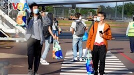 FILE - This handout picture taken on November 30, 2020 and released by Charles Darwin University shows foreign students disembarking from an international flight at Darwin Airport in Darwin. (Photo by JULES / Charles Darwin University / AFP)