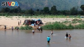 Displaced people from Myanmar wade across the river from Thailand into Myanmar, as seen from Mae Sot, Thailand, Feb. 7, 2022.